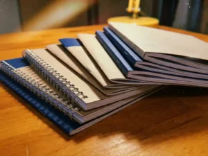 Verzameling vers gedrukte brochures met verschillende bindmethoden op houten werkblad, spiraalgebonden boekjes en geniet catalogi
