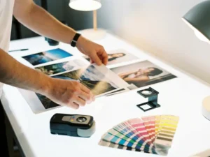 Professionele fotograaf past hoogresolutie foto's aan op witte lichtbak met kleurkalibratie tools en CMYK kleurstalen